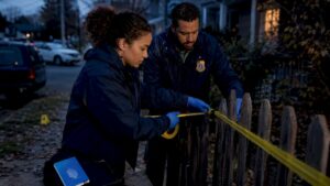 Investigators placing police tape at crime scene