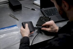 Hands connecting forensic write-blocker to hard drive